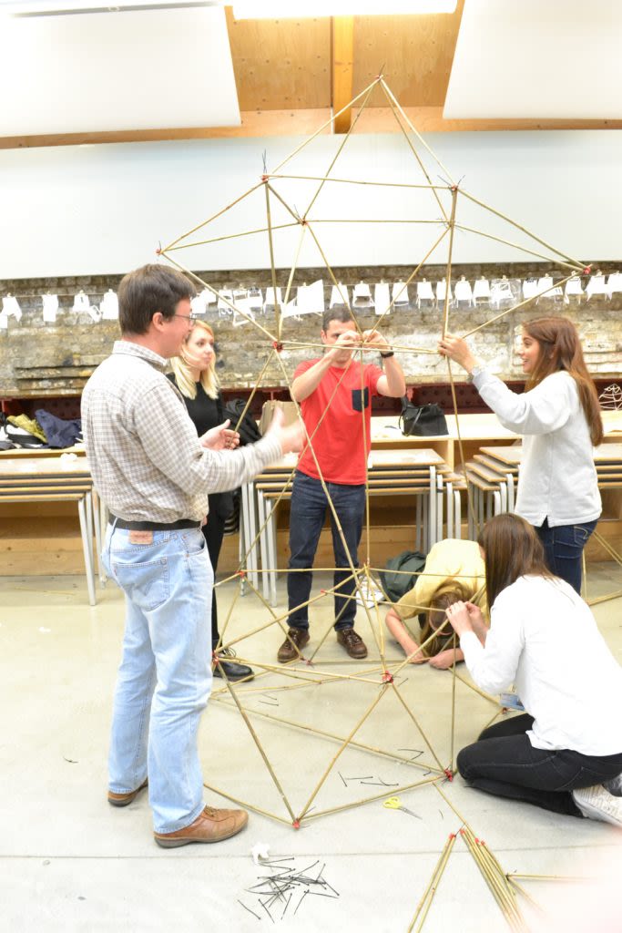 A group of participants works on building a structure from wooden sticks.