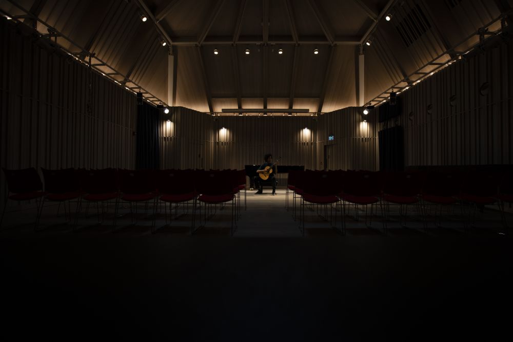 theatre in darkness with dim lights and man playing guitar on the  stage