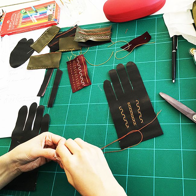 Desk with black leather gloves cut to size, being worked on in the studio.