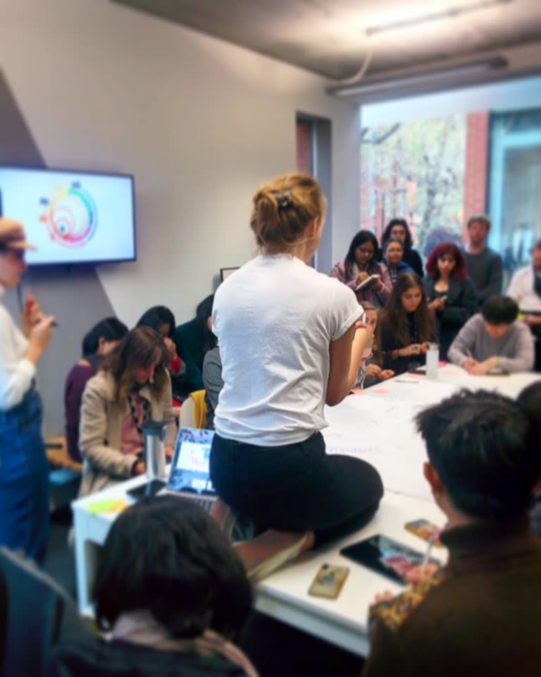 Cathryn Hall kneeling on a table in a crowded room