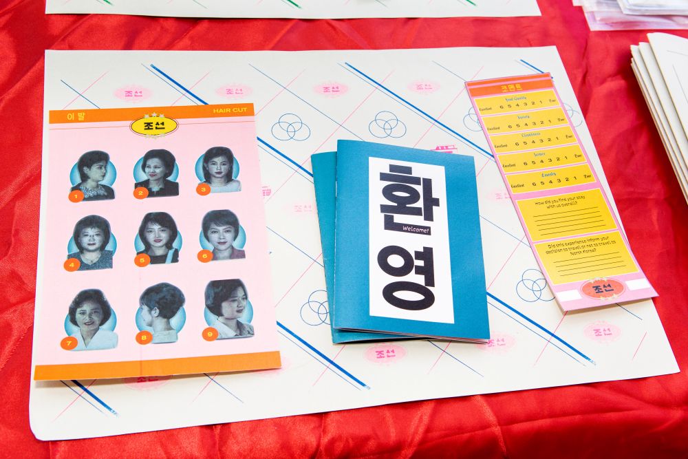 Table-top of leaflets and designs in reds, pinks, blues, yellows. 