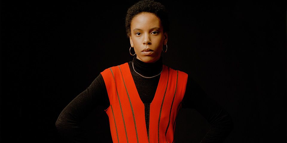 A women wearing a bright set waistcoat stood in front of a black background