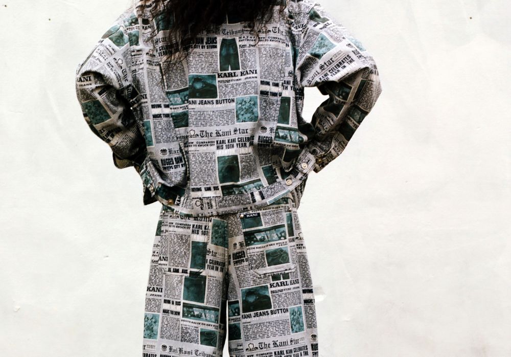 Photograph of a man wearing a newspaper print denim jacket, shot from the back