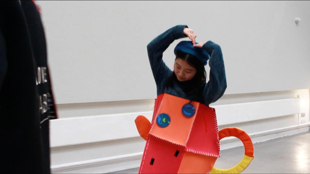 Student dressed in orange teacup outfit posing as a teapot.