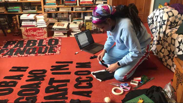 Woman sitting on floor arranging black fabric letters