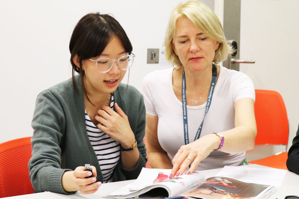 Schelay McCarter working with a student, looking at a magazine.