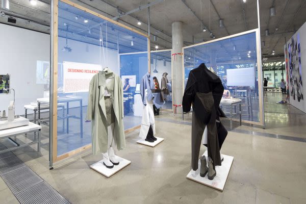 Photograph of the gallery with three mannequins displaying garments 
