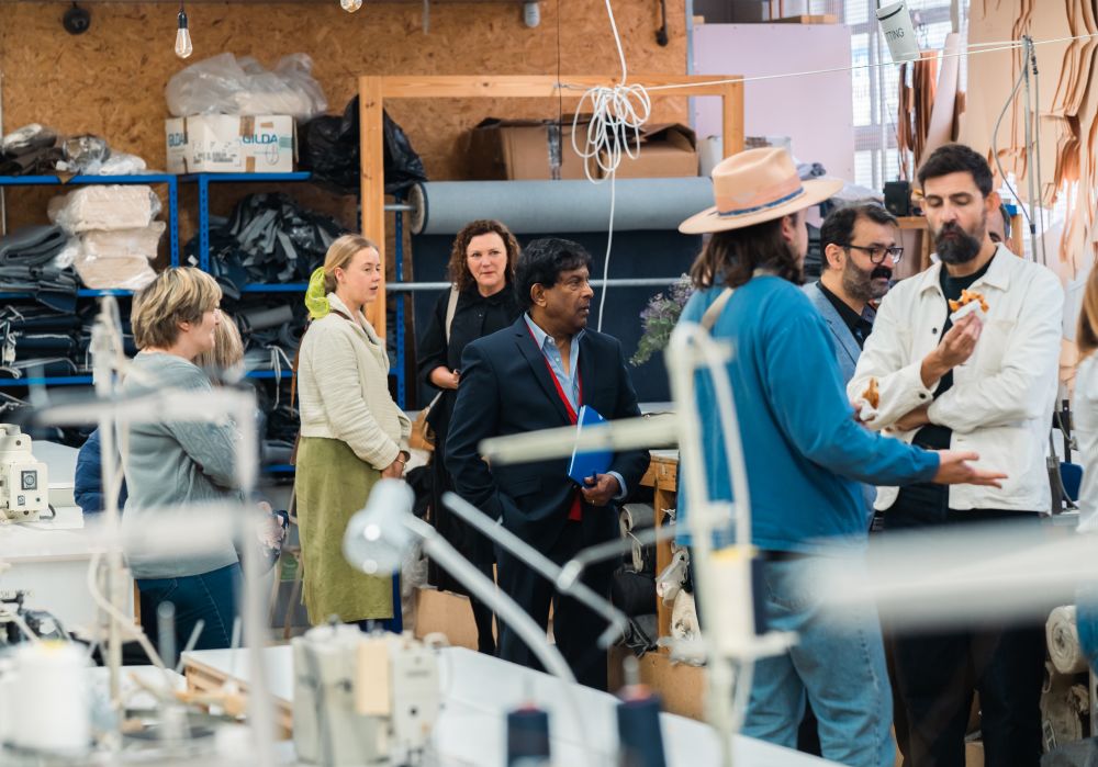 a room with textiles and sewing machinery and people talking in the middle of the room