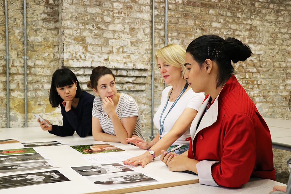 Schelay McCarter working with students, looking at photographs of fashion models.