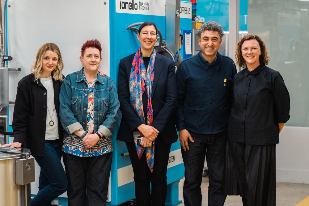 five people posing in a line in front of a machine 