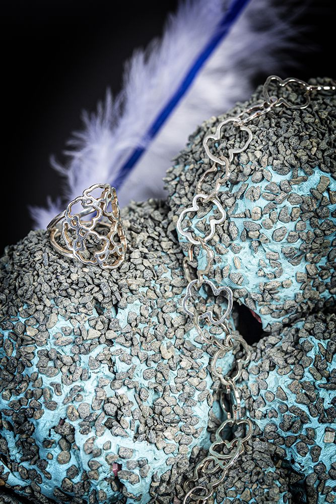Work by Visual Merchandising - Interiors students, taken by Sarah Manning. Silver jewellery sitting on a blue and grey rock.