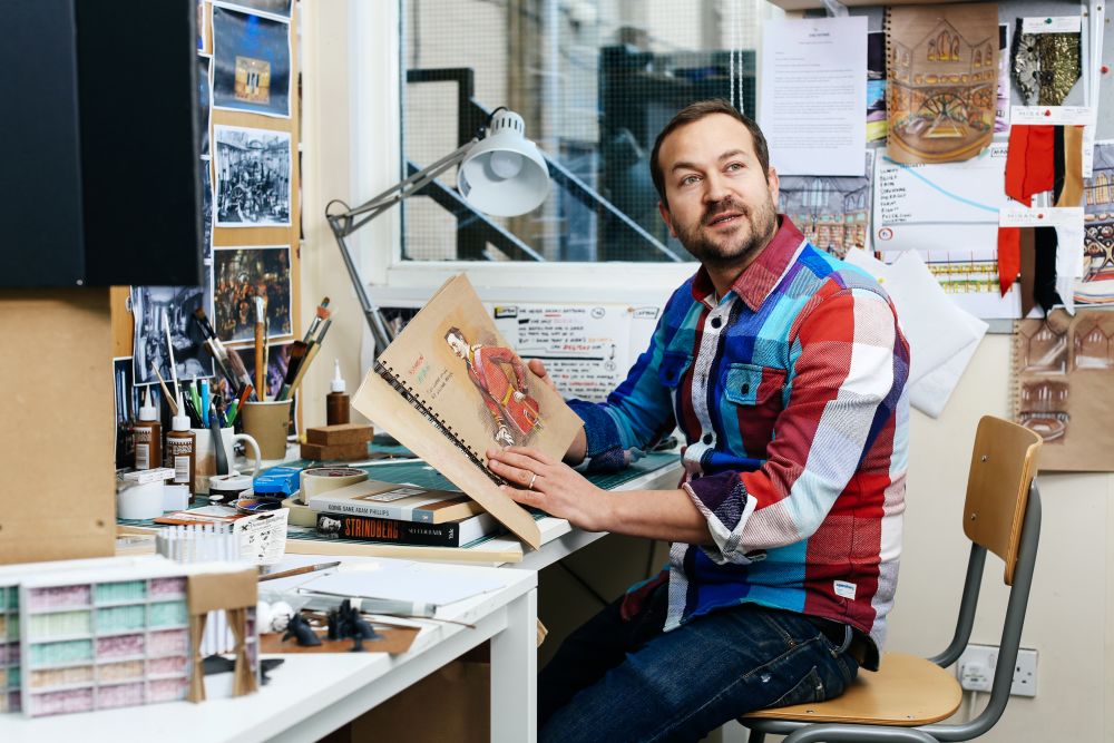 Yoav Segal holding his sketchbook open.