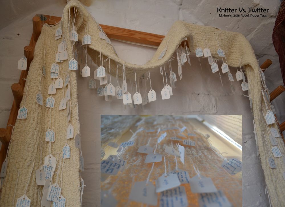 a picture of a long knitted fabric piece with paper tags hanging from it