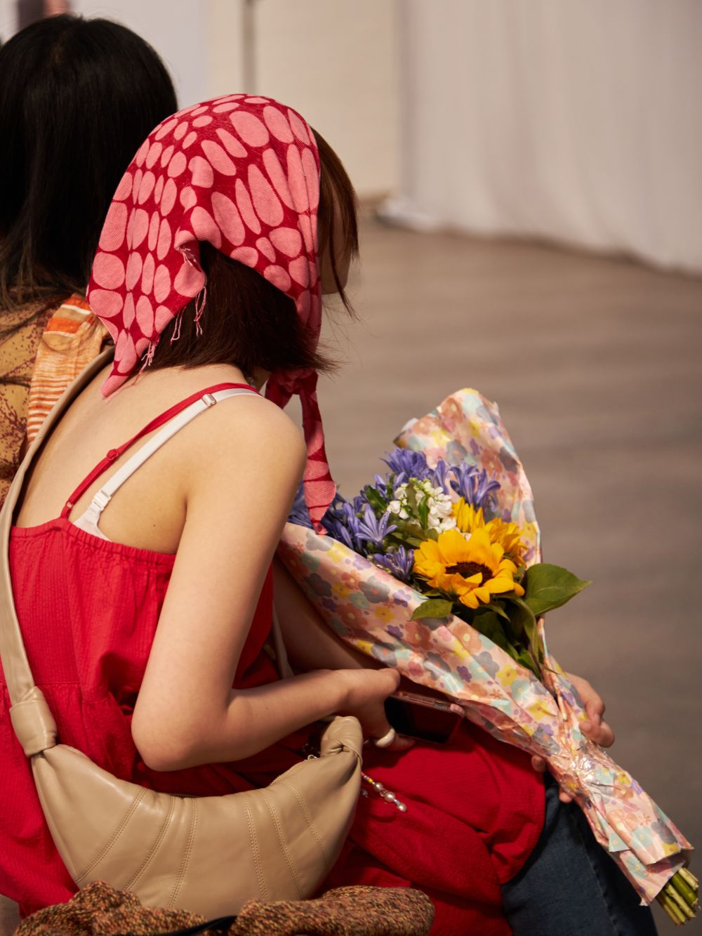 Behind the head shot of a student holding a bouqet of flowers