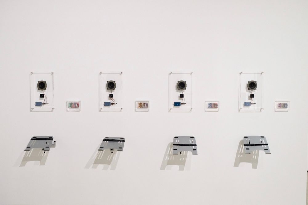 An installation of four electronic devices on a white wall