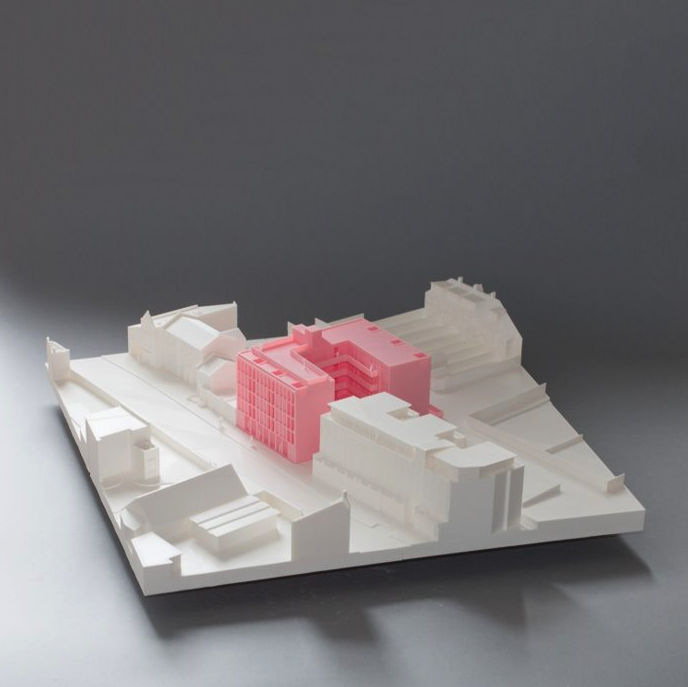 a 3D printed building model in pink surrounded by buildings in white