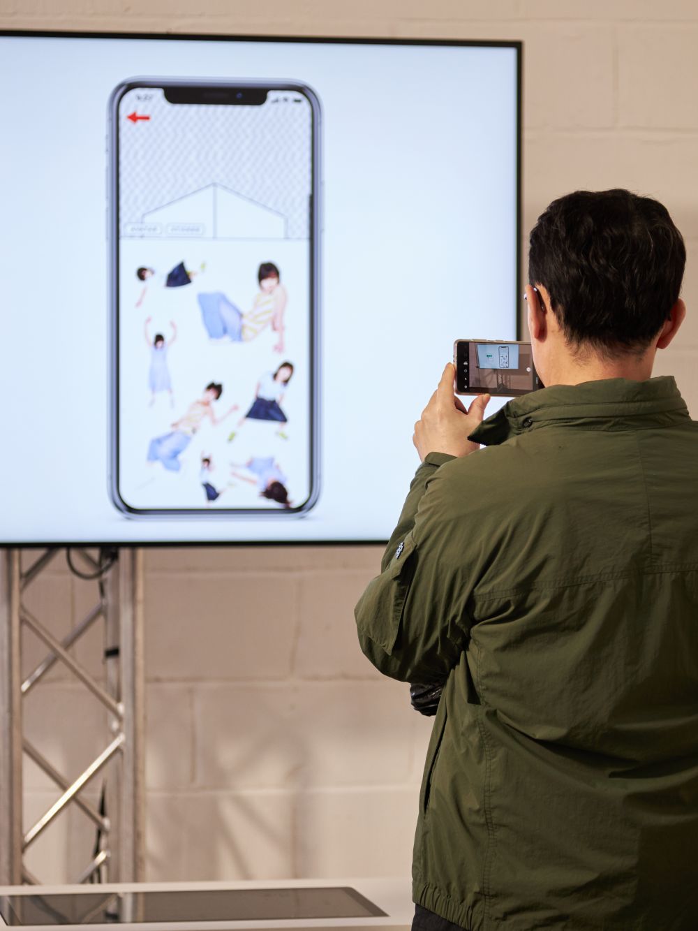 Person photographing a screen using their phone