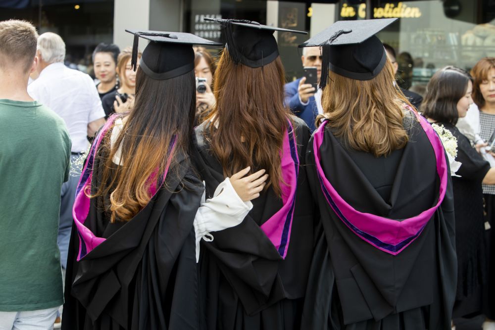 The back of three female graduates having a photograph taken