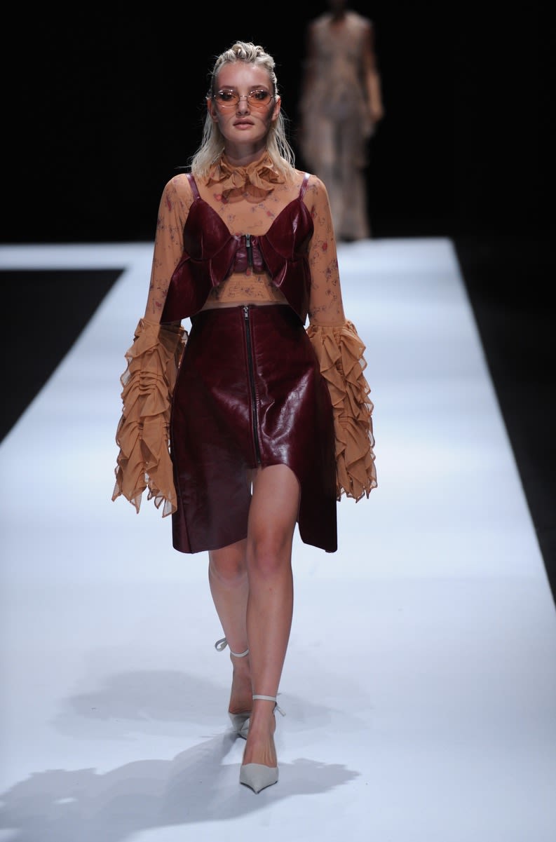 Female model wearing a two piece suit with red skirt and top designed by Juhee Song