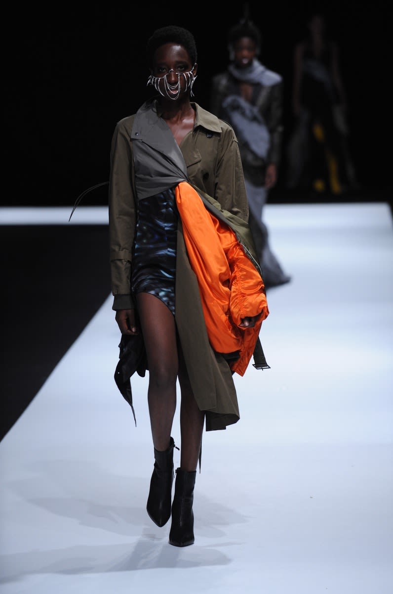 Female model wearing asymmetrical dress in orange, black and dark green tones designed by Yelim Cho