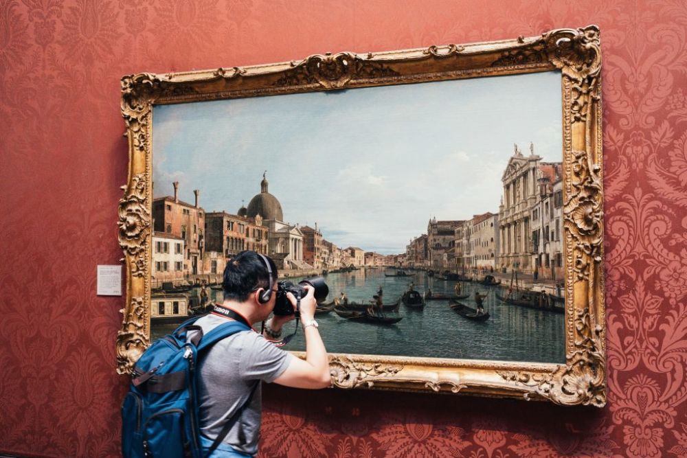 person photographing a painting in a museum