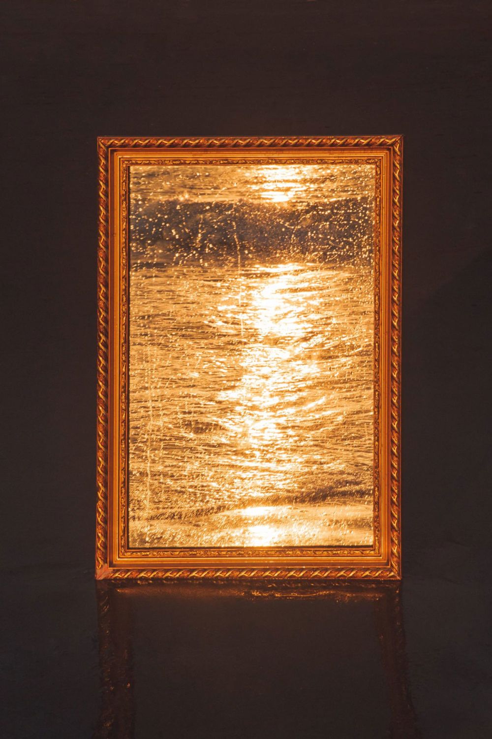 Image depicts a mirror reflecting golden sunlight over water.