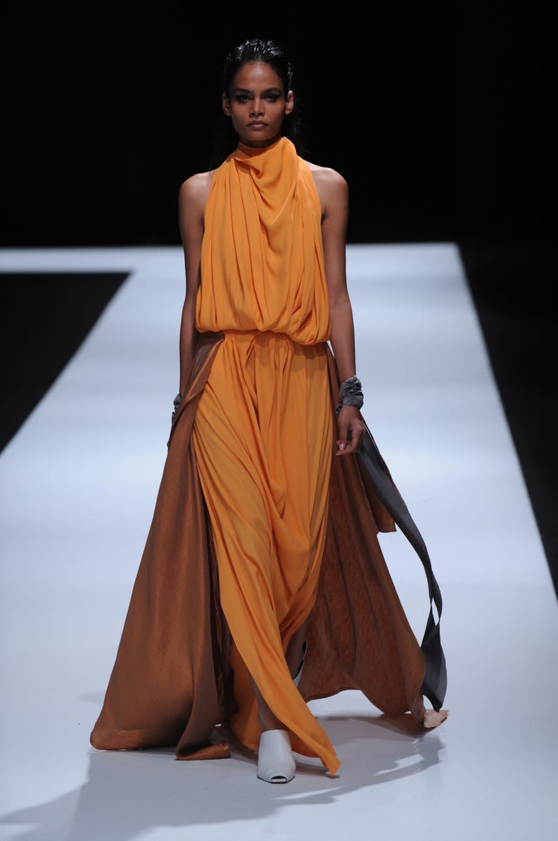Female model wearing long orange dress designed by Jacqueline Lee