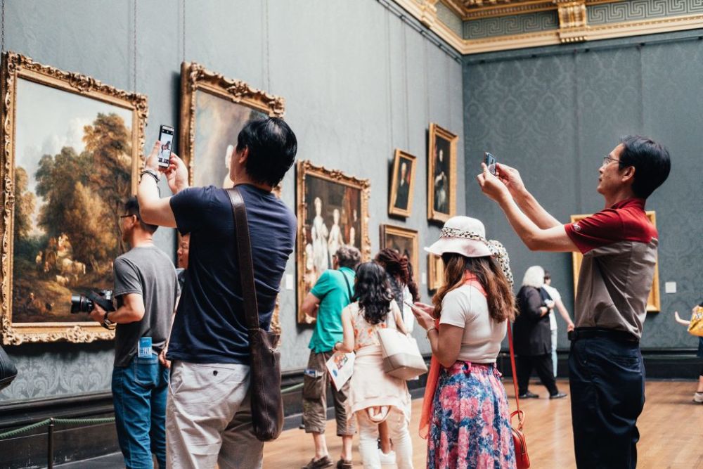 people photographing a painting in a museum