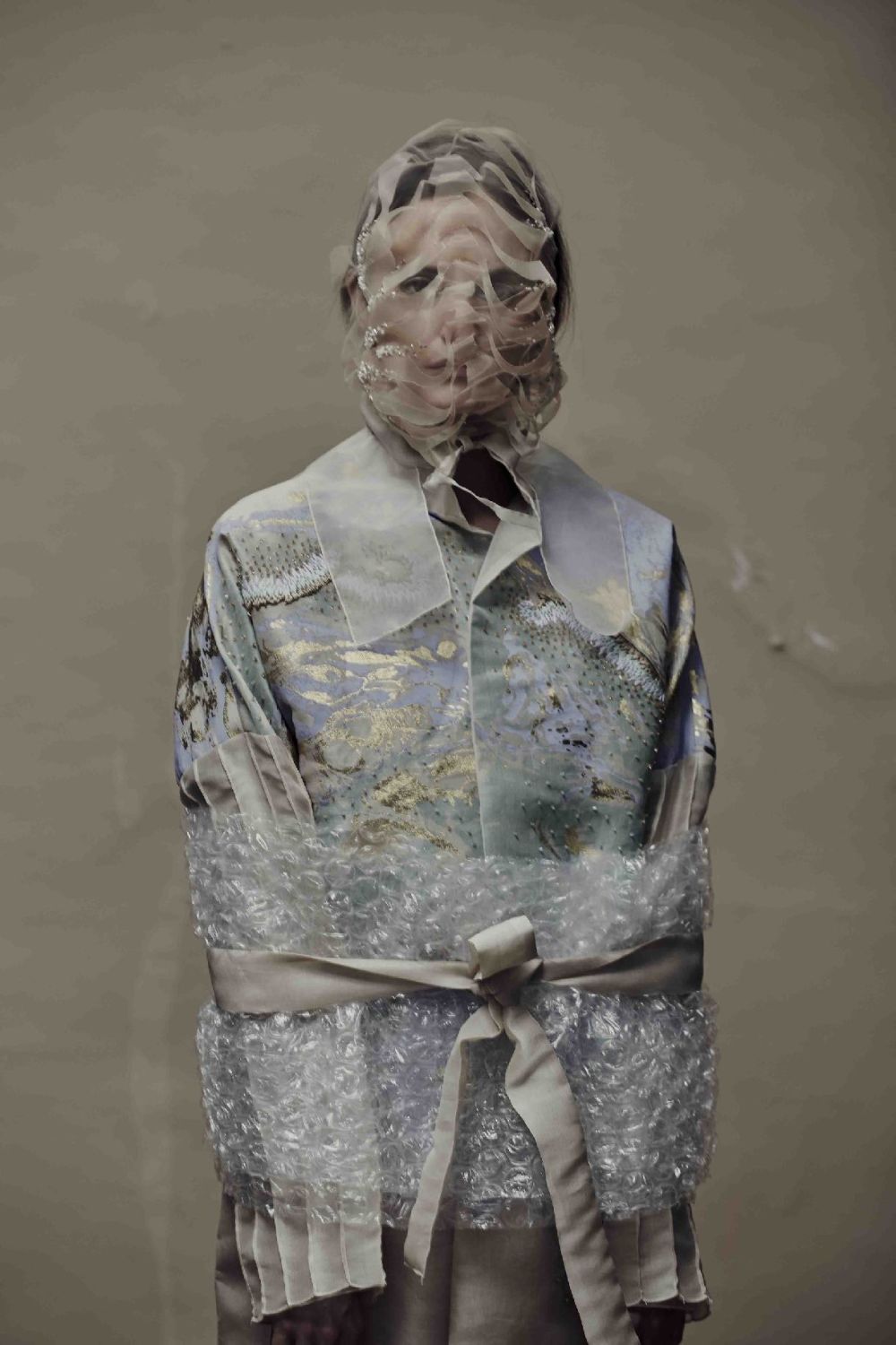 A model is wrapped in bubblewrap and pastel-coloured materials.