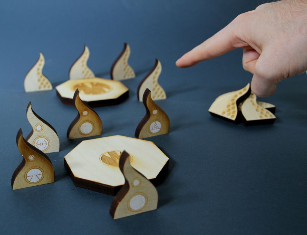 image of game made out of 3d wooden pieces which are displayed on a table. there is hand pointing to the game
