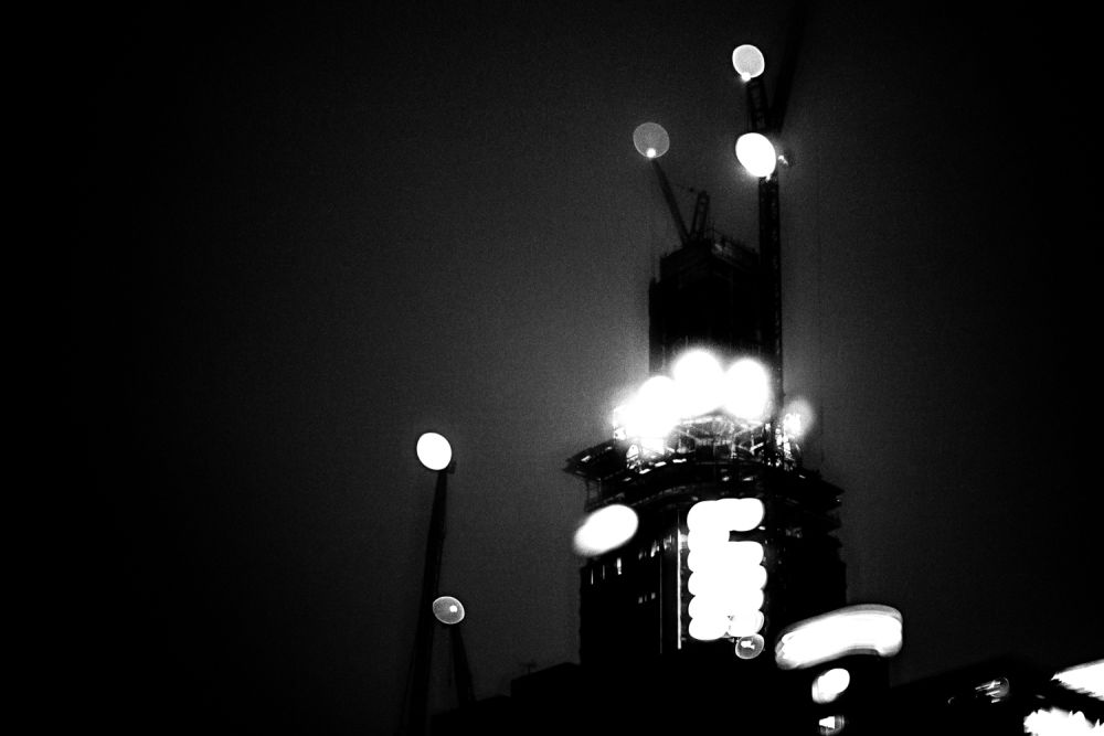 Blurry black and white image of tall building under construction.