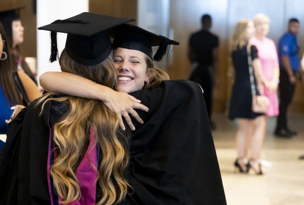 Two female graduates hugging.