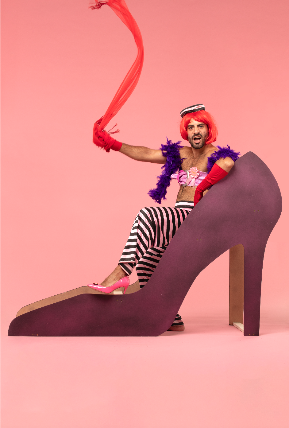 Man with feather boa sitting in giant shoe