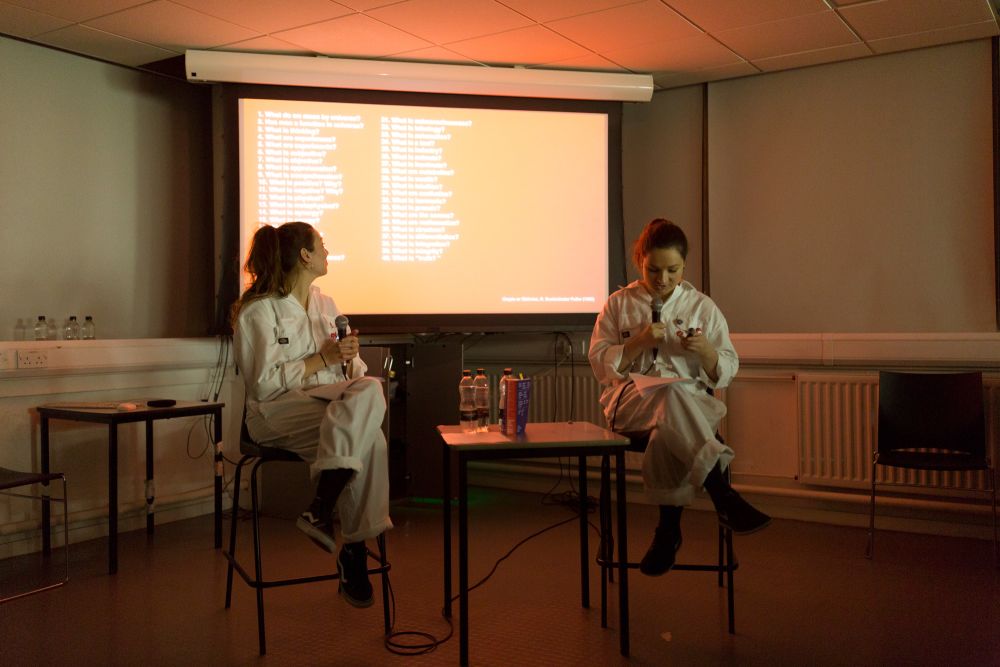 Participants wearing boiler suits on stage presenting.