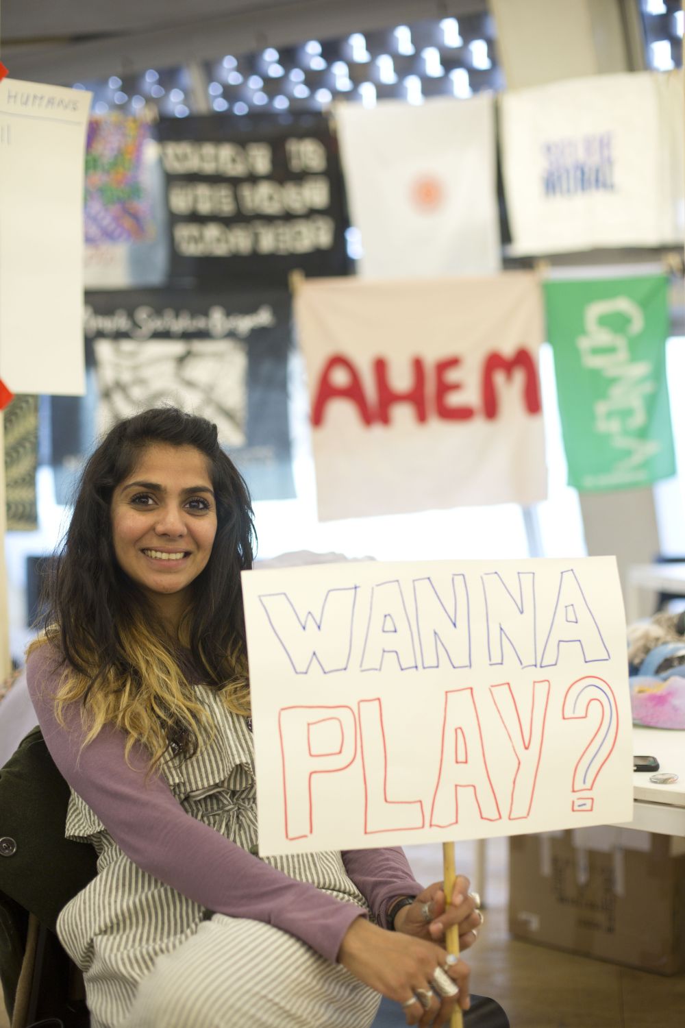 Woman holding sign saying 'wanna play?'