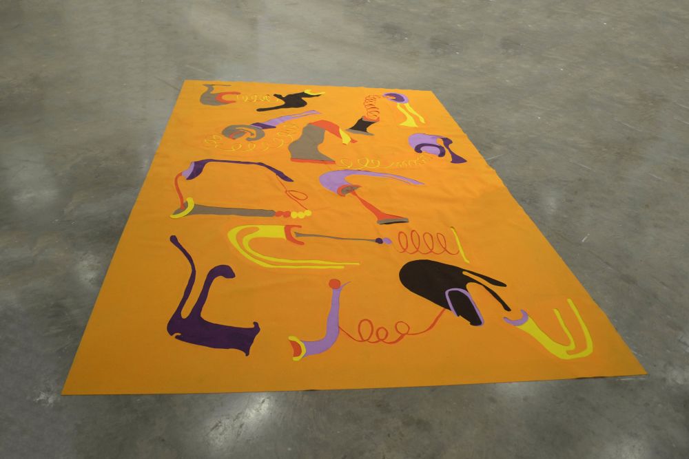A bright orange carpet decorated with purple, yellow and grey shapes