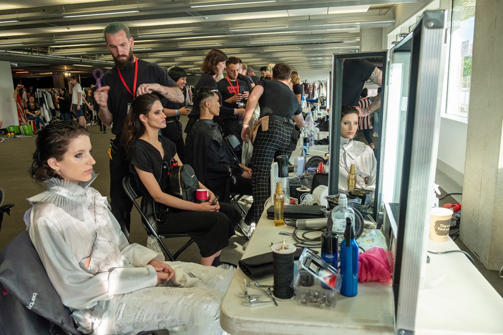 A row of female models getting their makeup done backstage