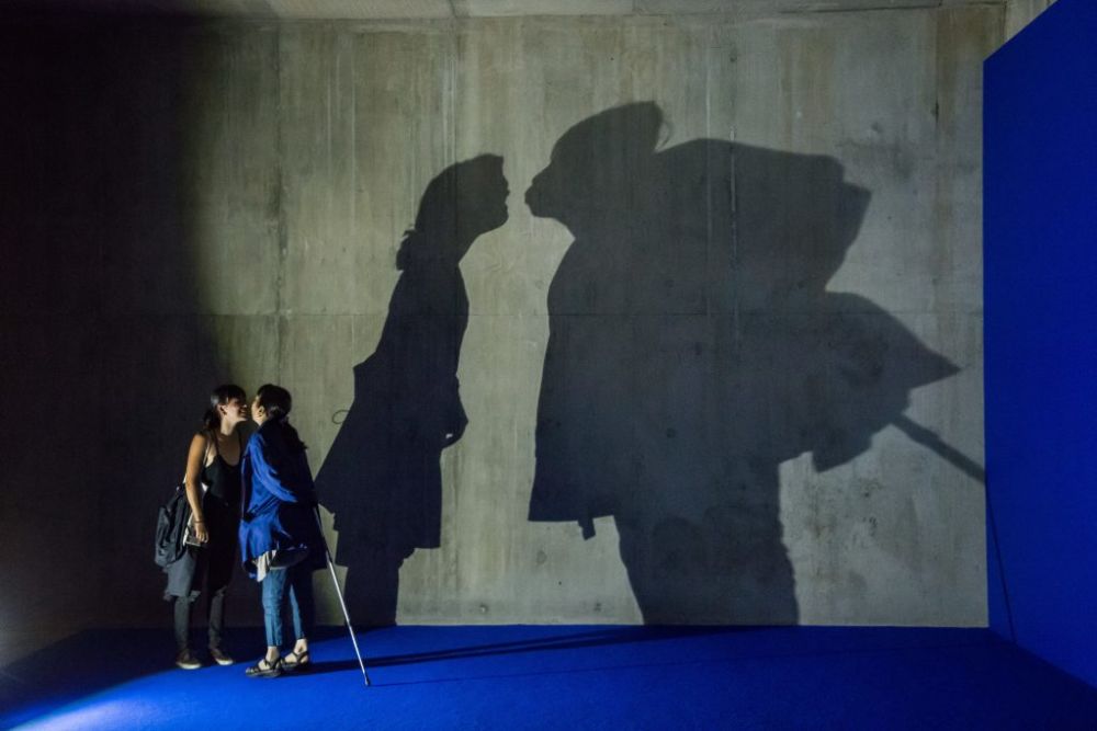 people kissing with their shadow on the wall behind them
