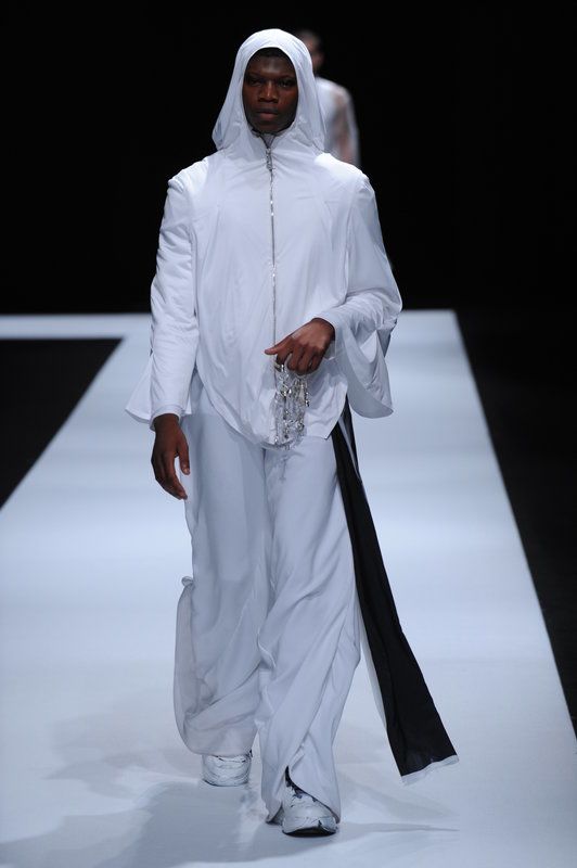 Male model wearing all white clothing with white hood.