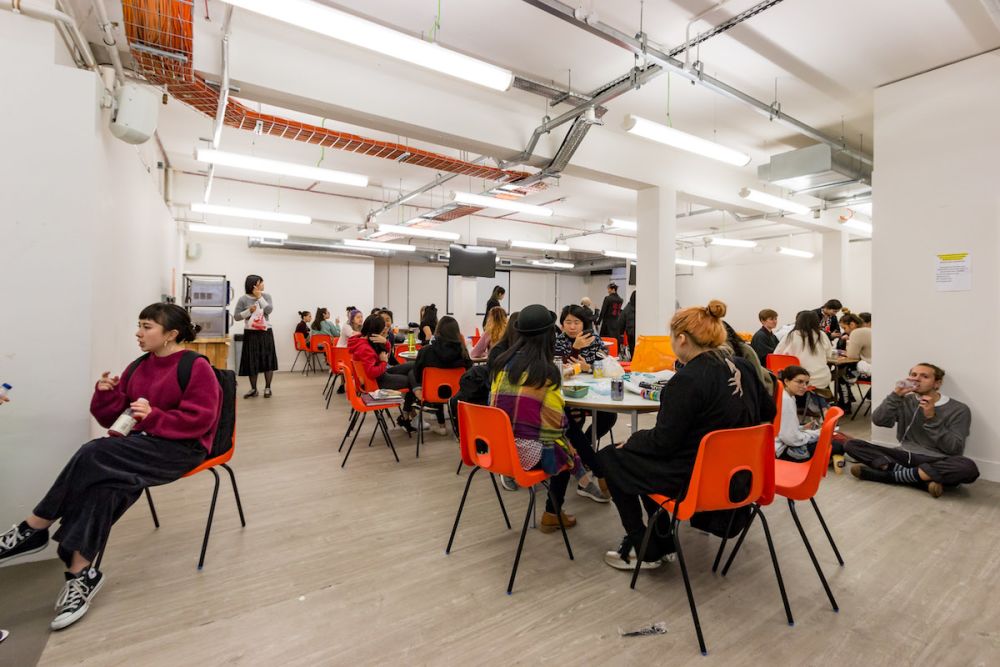 Students at a desk eating lunch at Central Saint Martins' Archway campus