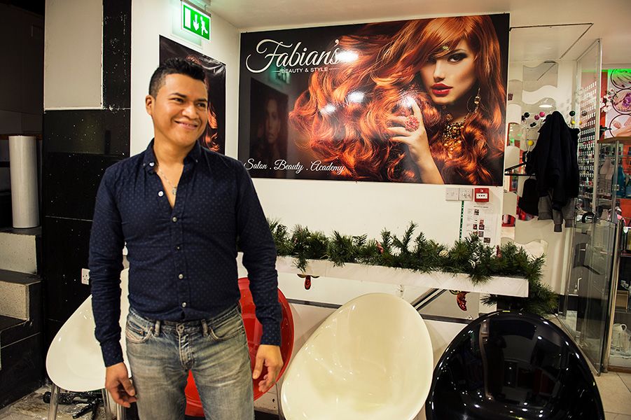 Fabian, owner of Fabian Beauty Stylist hairdressing salon in Elephant Road, and his new logo, designed by Caley Dewhurst, in the background.