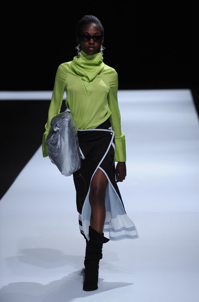 Female model wearing long sleeve neon green top and black and white long skirt designed by Yujin Seo