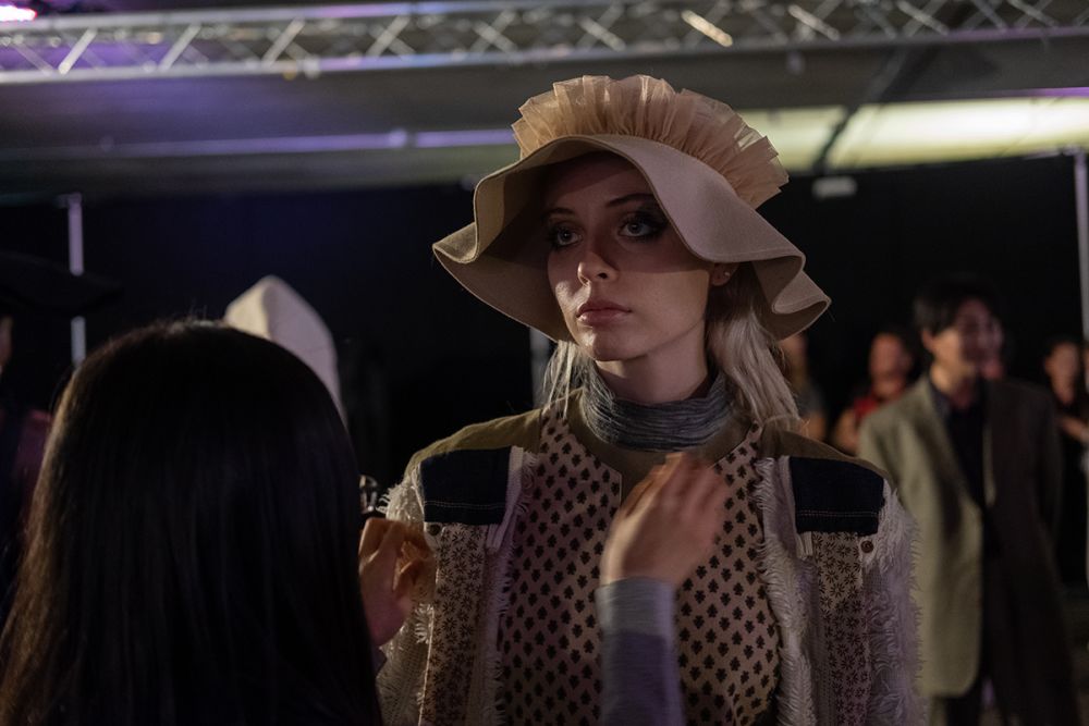 Model wearing a camel bonnet having her outfit altered backstage