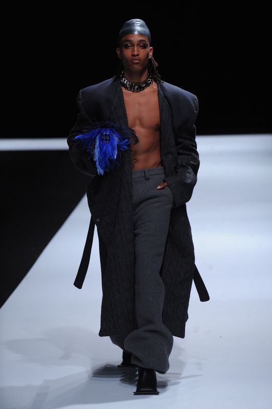Topless male model with ankle length blazer and hat