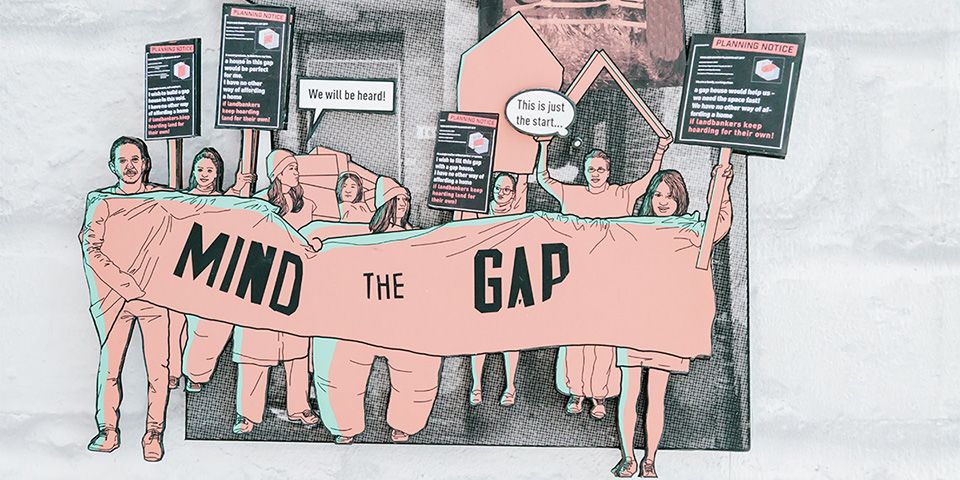 A cut out illustration of a group of people holding up a banner that reads 'Mind the gap'