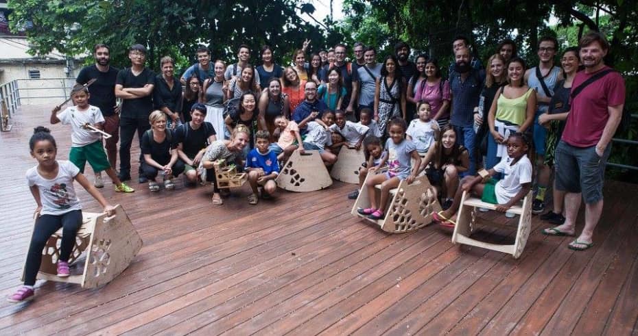 A group photo of people stood on  wooden decking with wooden structures 