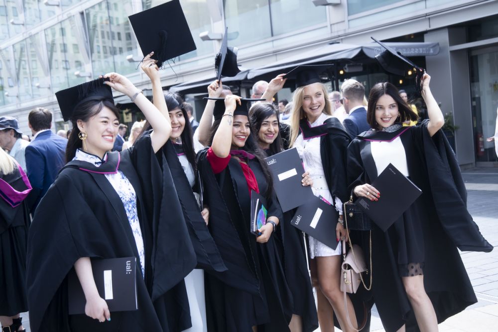Six female graduates having a photograph and throwing their graduation hats in the air.
