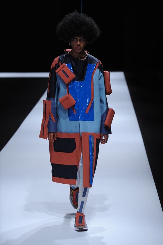 Male model with orange and blue long coat with cubes attached