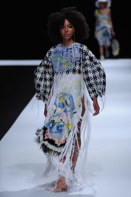 Female model wearing decorative dress with multiple knitted fabrics and colours