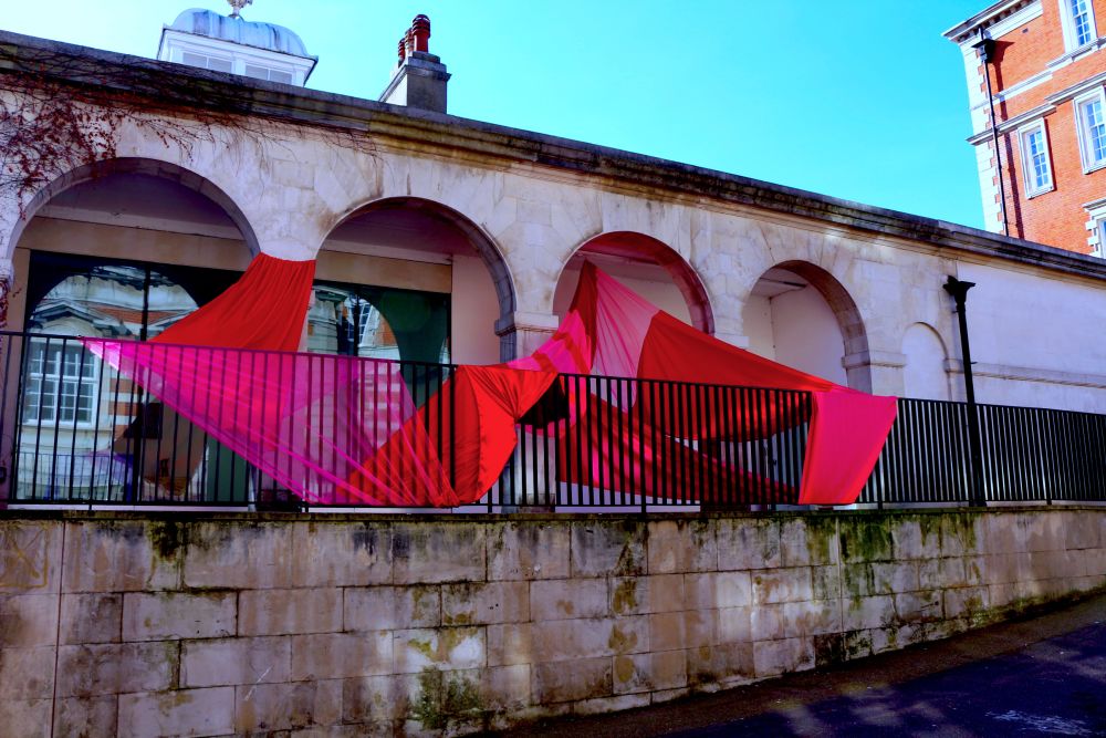 a picure of a pink and red fabric installation outside an old building